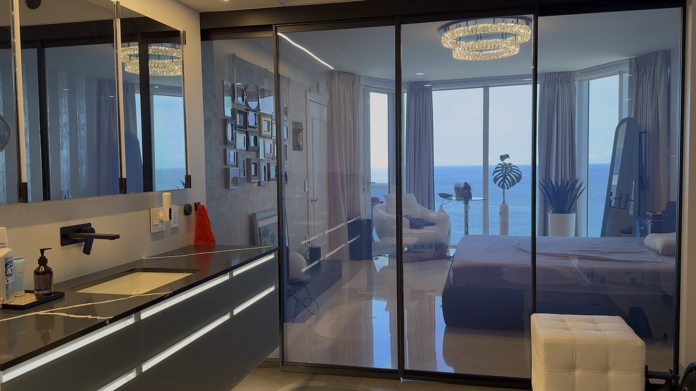 Suite residencial con división de vidrio transparente antes de activar Smart Glass